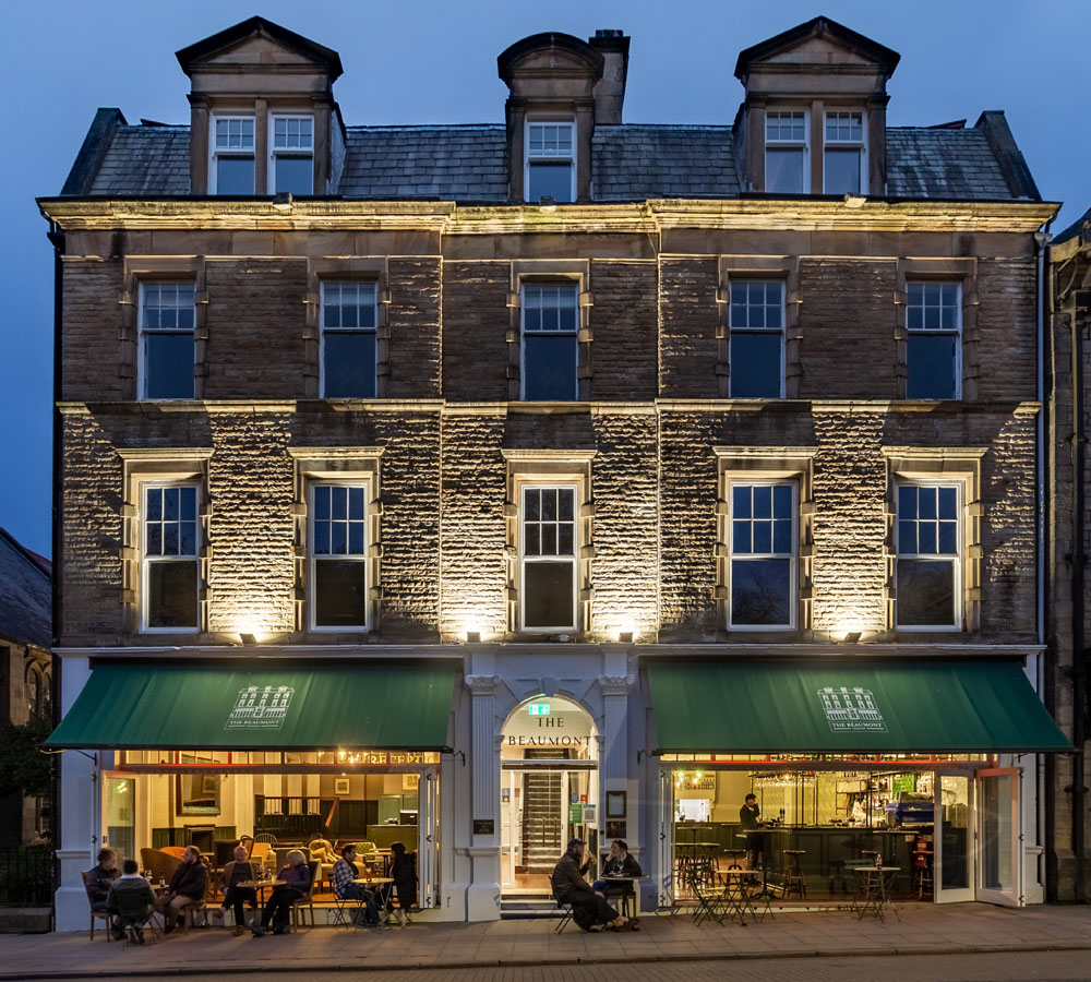 The Beaumont Hotel, Hexham: stone Victorian building with green awnings, photographed at twilight